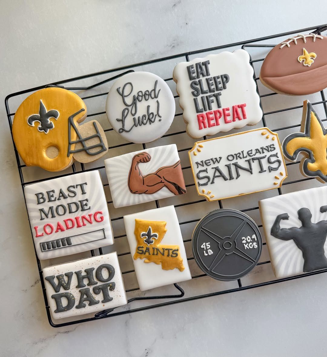 Decorated sugar cookies featuring footballs and New Orleans Saints themes on a cooling rack.