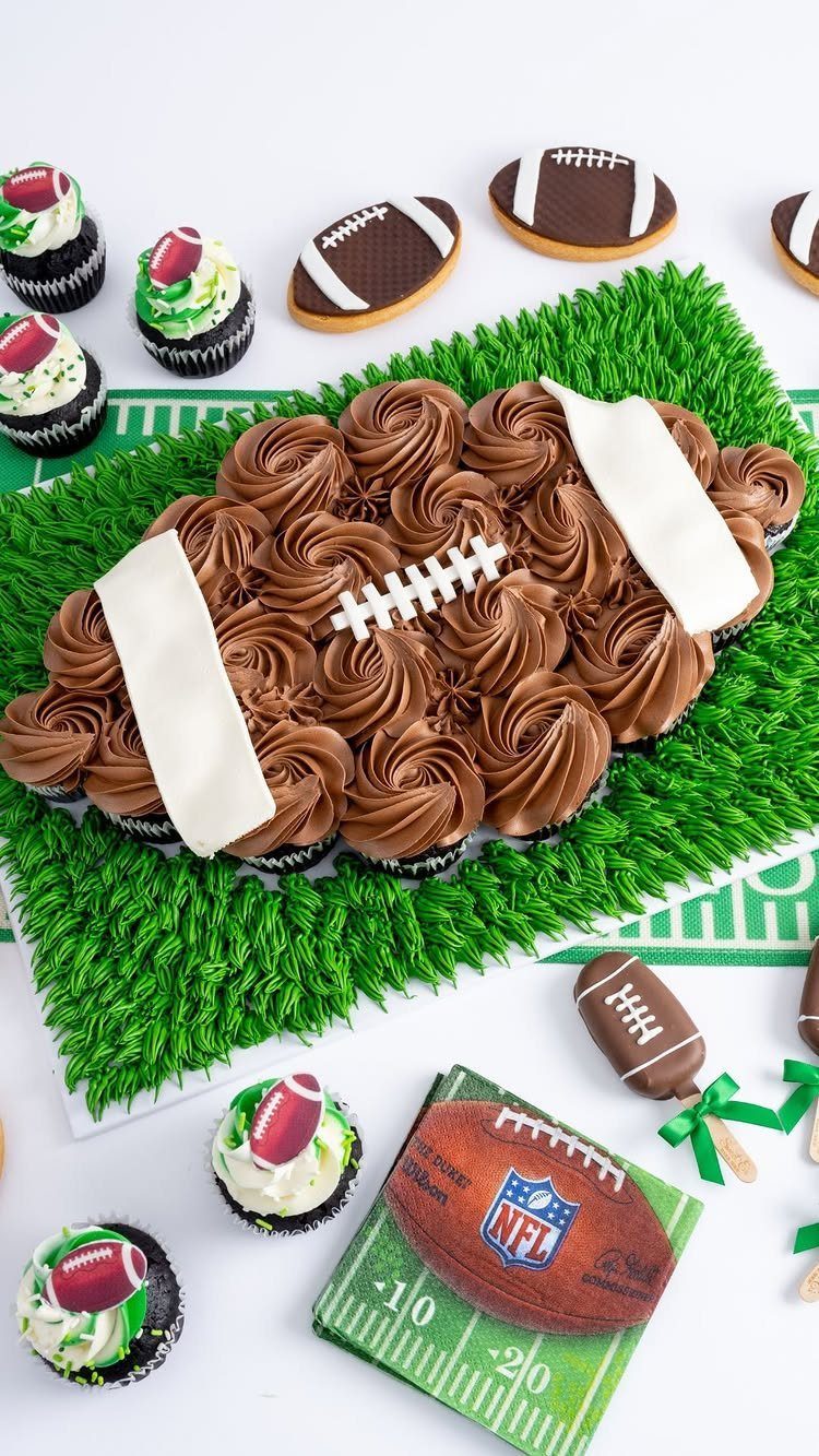 Football-shaped chocolate cupcake dessert on green grass with football cookies and cupcakes.