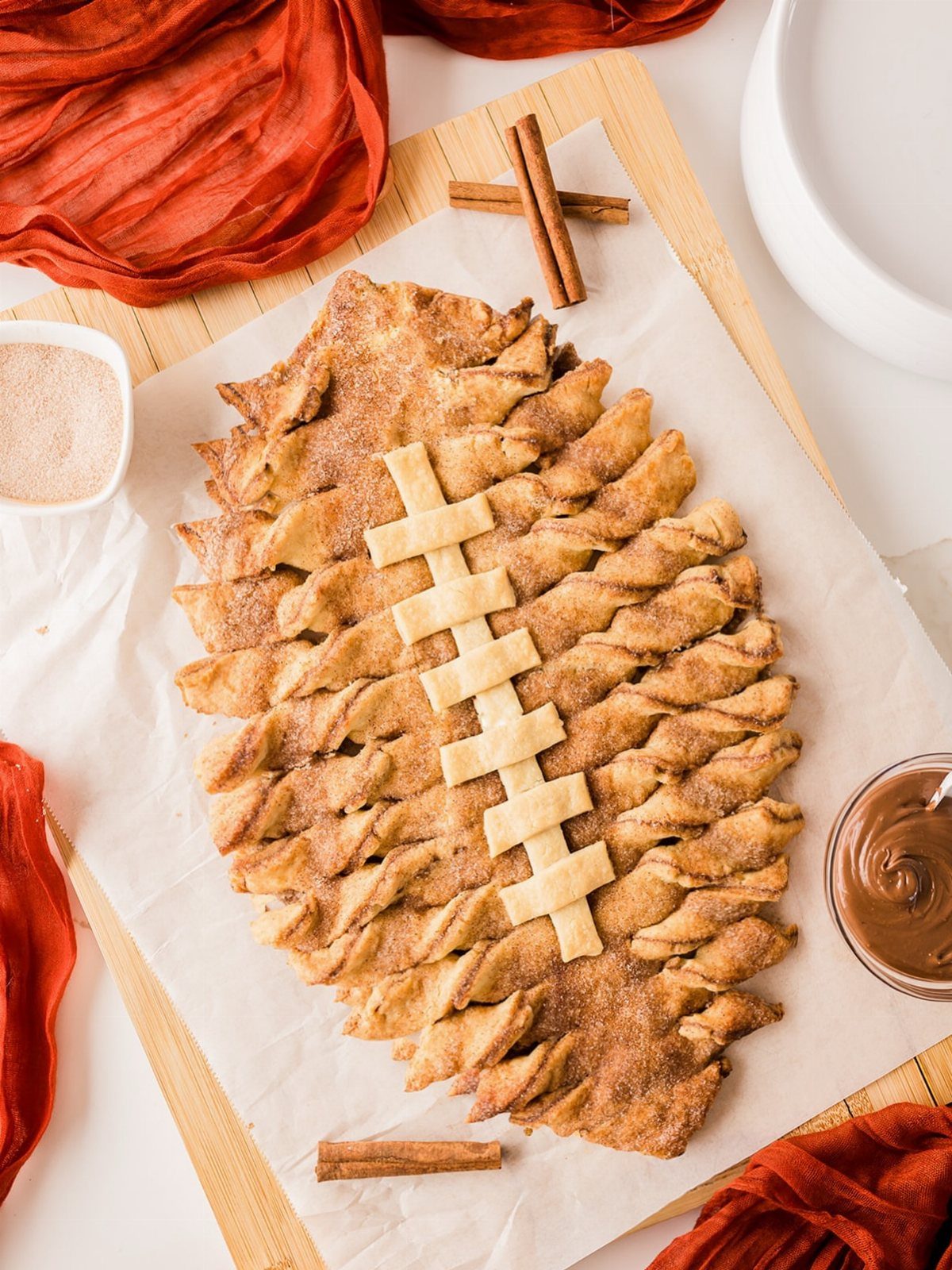 Football-shaped pull-apart pastry with cinnamon sugar and chocolate dipping sauce on wood.