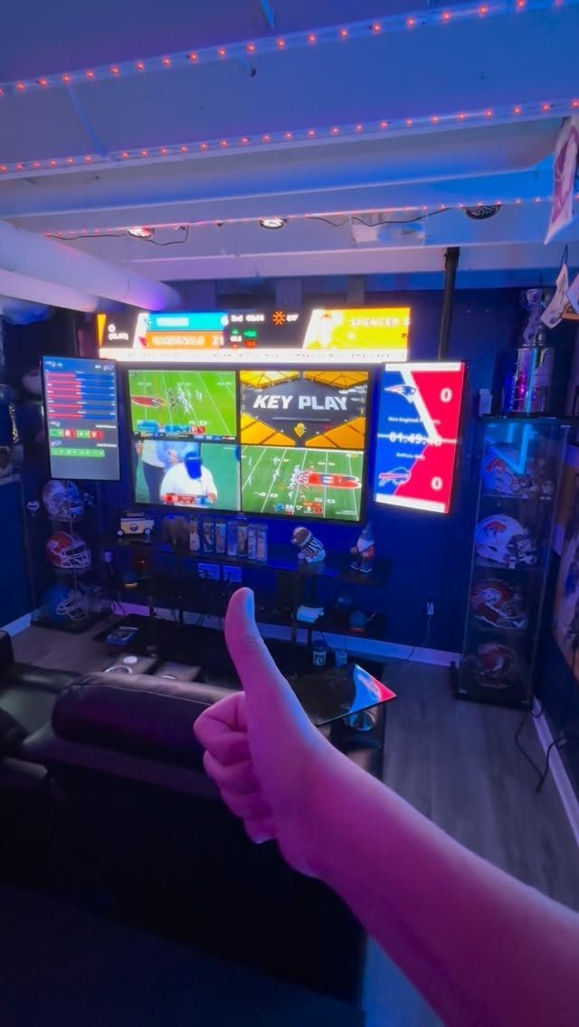 Multiple television screens displaying football games in a blue-lit sports fan room.