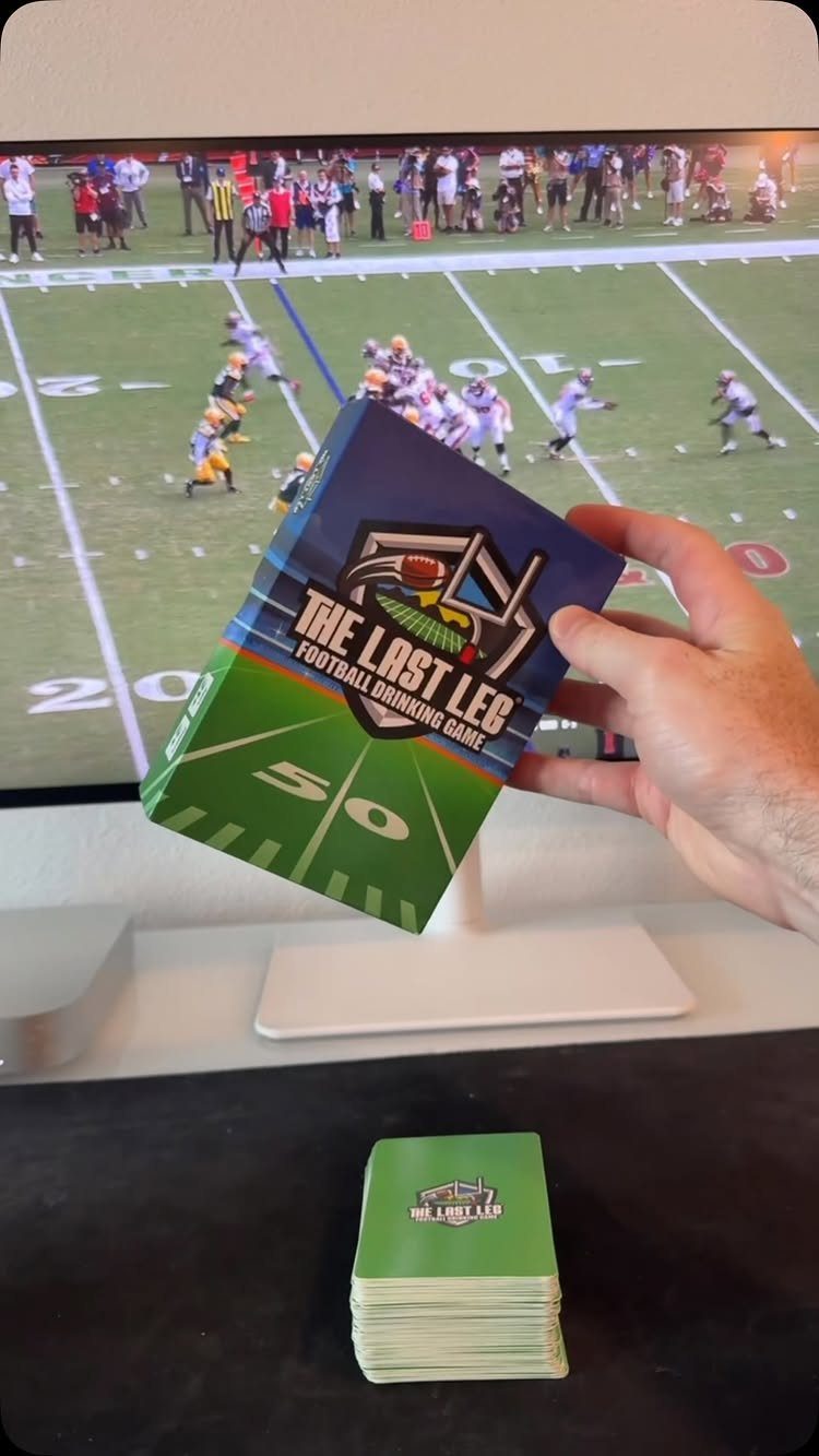 Football drinking game box and cards held in front of a football game screen