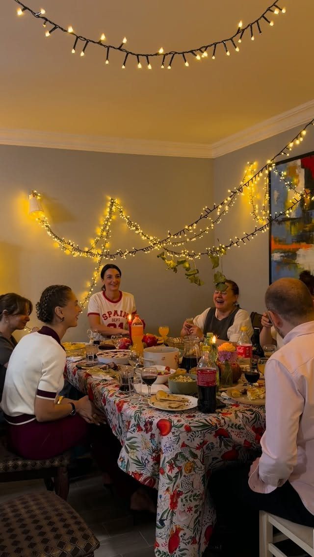 People dining at a table with warm fairy lights strung across the ceiling.