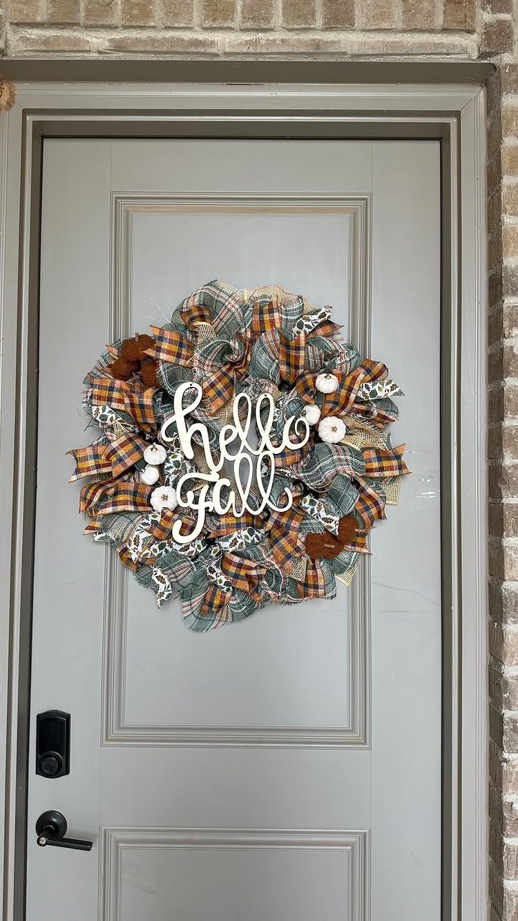 Autumn wreath with plaid fabric and hello Fall sign on a grey door