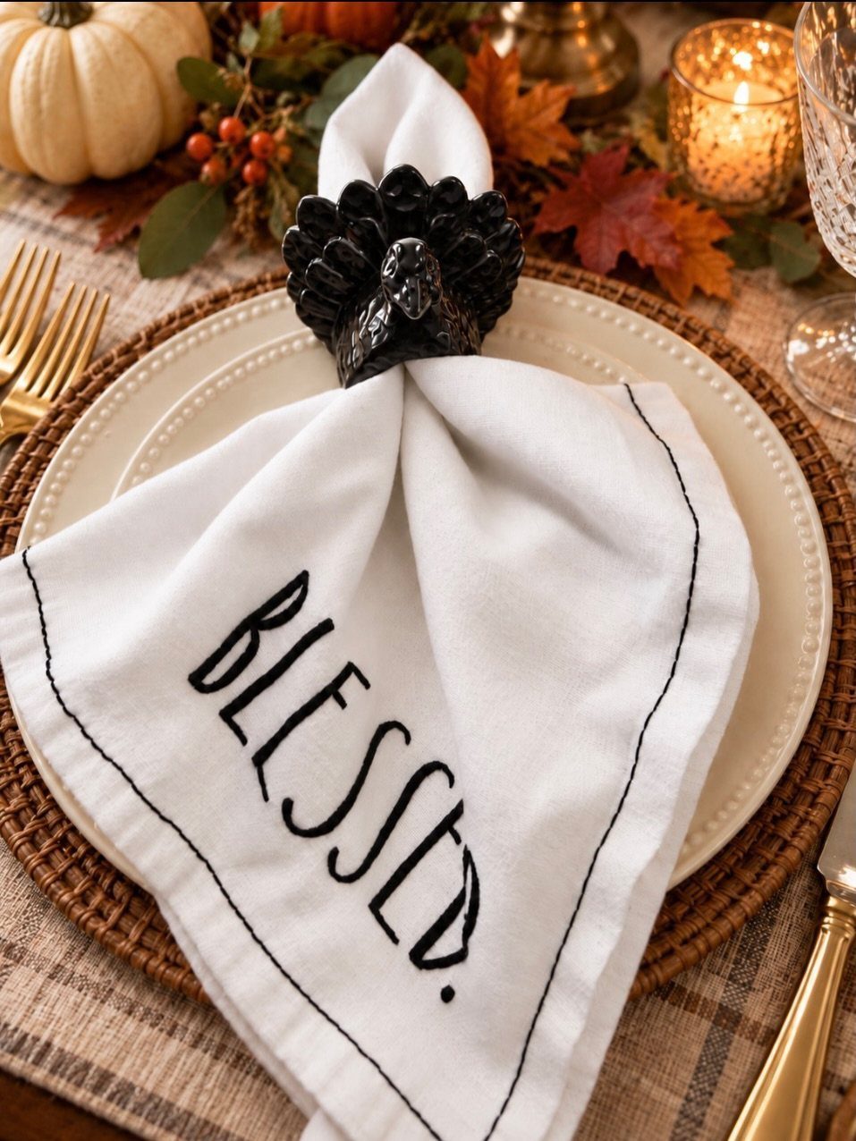 White embroidered napkin with a black turkey ring on a festive autumn table.