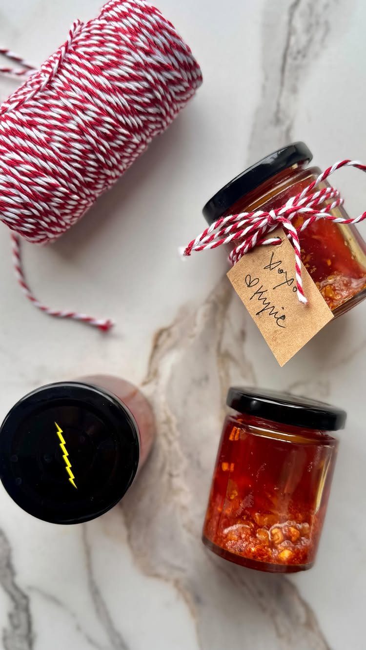 Two jars of red chili oil with a gift tag on marble surface.