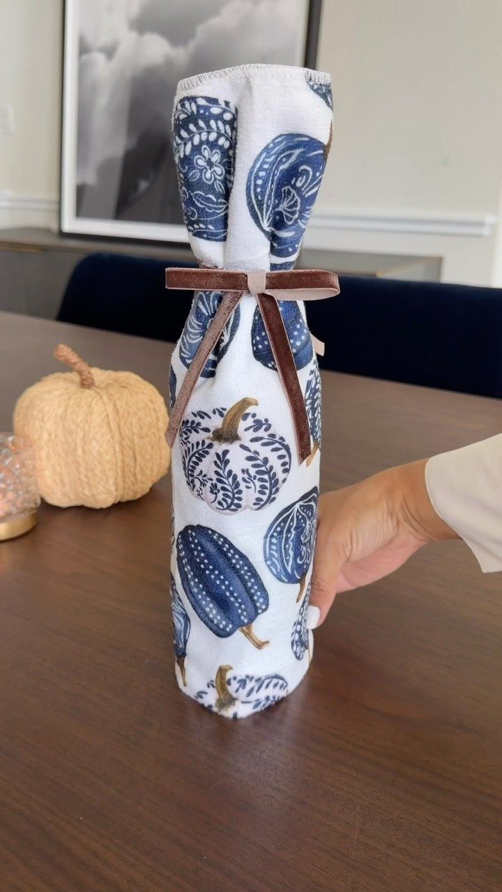 Bottle wrapped in blue pumpkin patterned fabric with a brown ribbon bow.