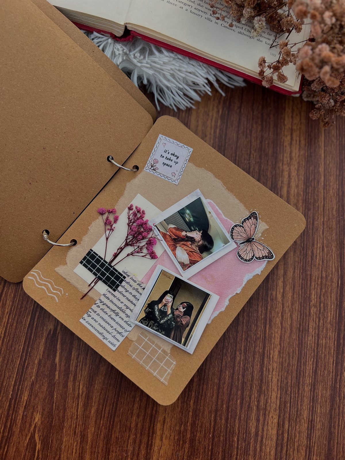 Handmade scrapbook page with polaroid photos, dried flowers, and a butterfly sticker.
