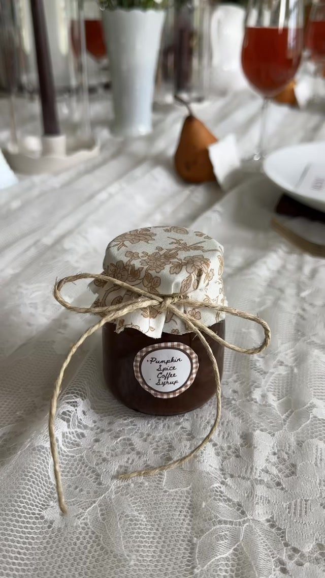 Small jar of pumpkin spice coffee syrup with twine bow on lace tablecloth