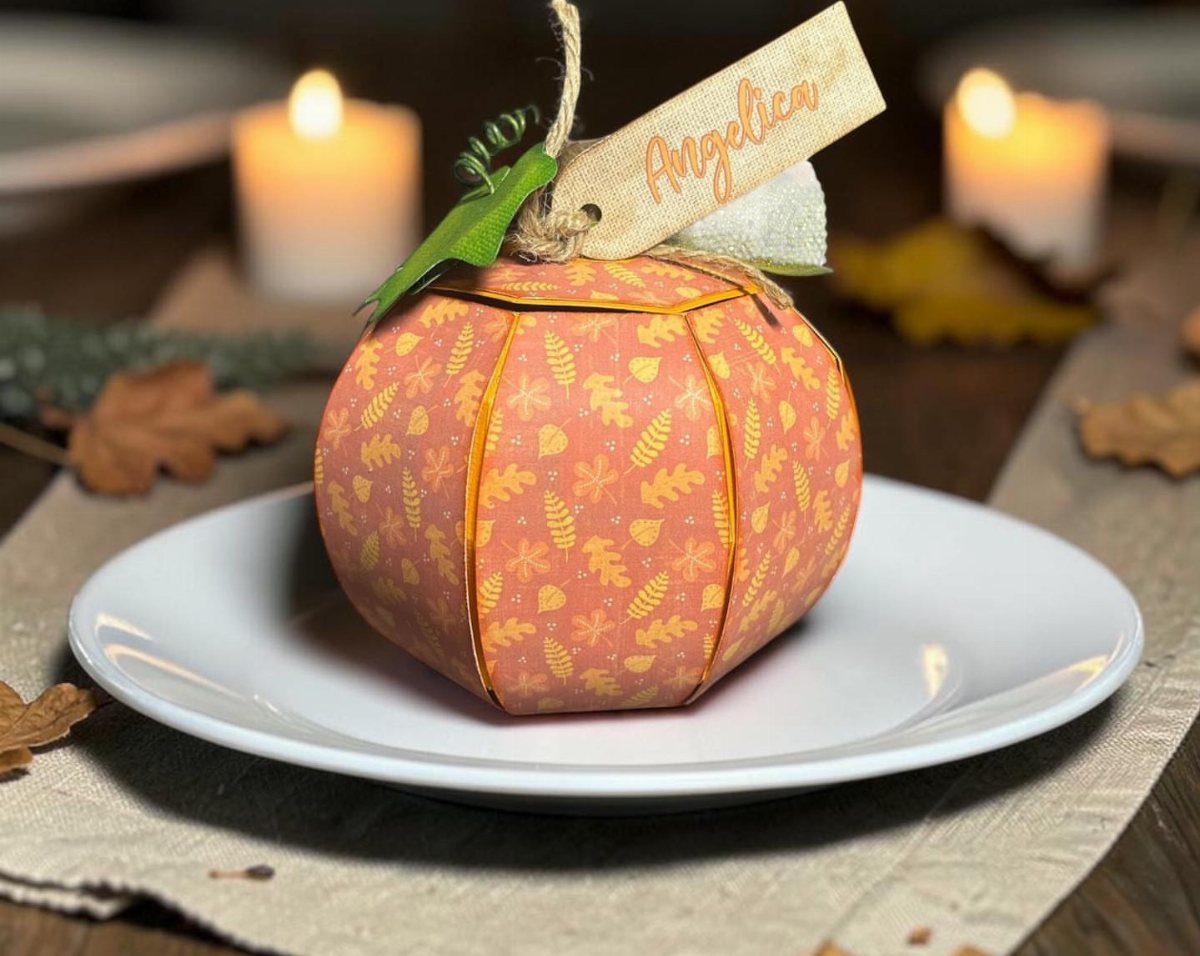 Pumpkin-shaped fabric gift wrap on a white plate with a personalized name tag.