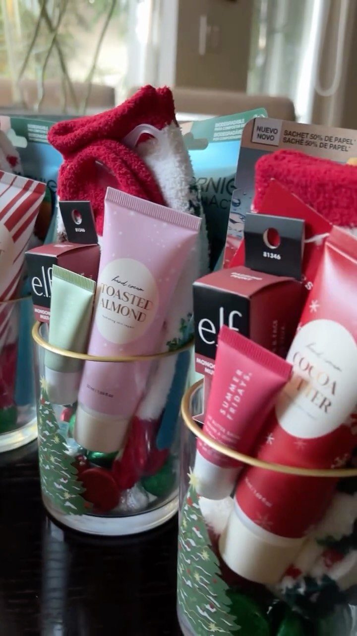 Beauty products and red fuzzy socks arranged in glass cups as gift sets.