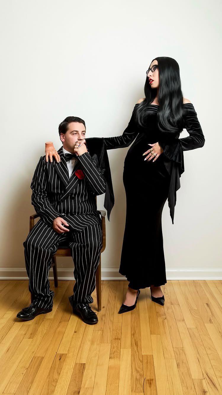 Man in pinstripe suit and woman in black velvet dress posing as a couple.