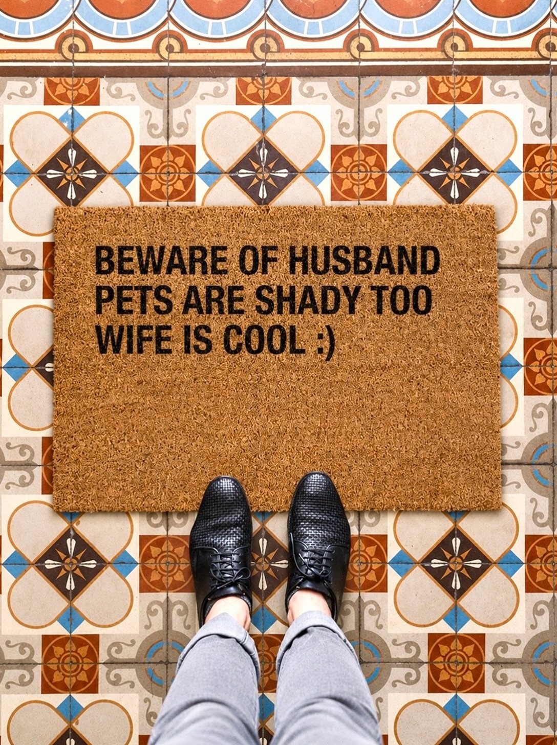 Brown coir doormat with funny text about husband and wife on patterned tiles.