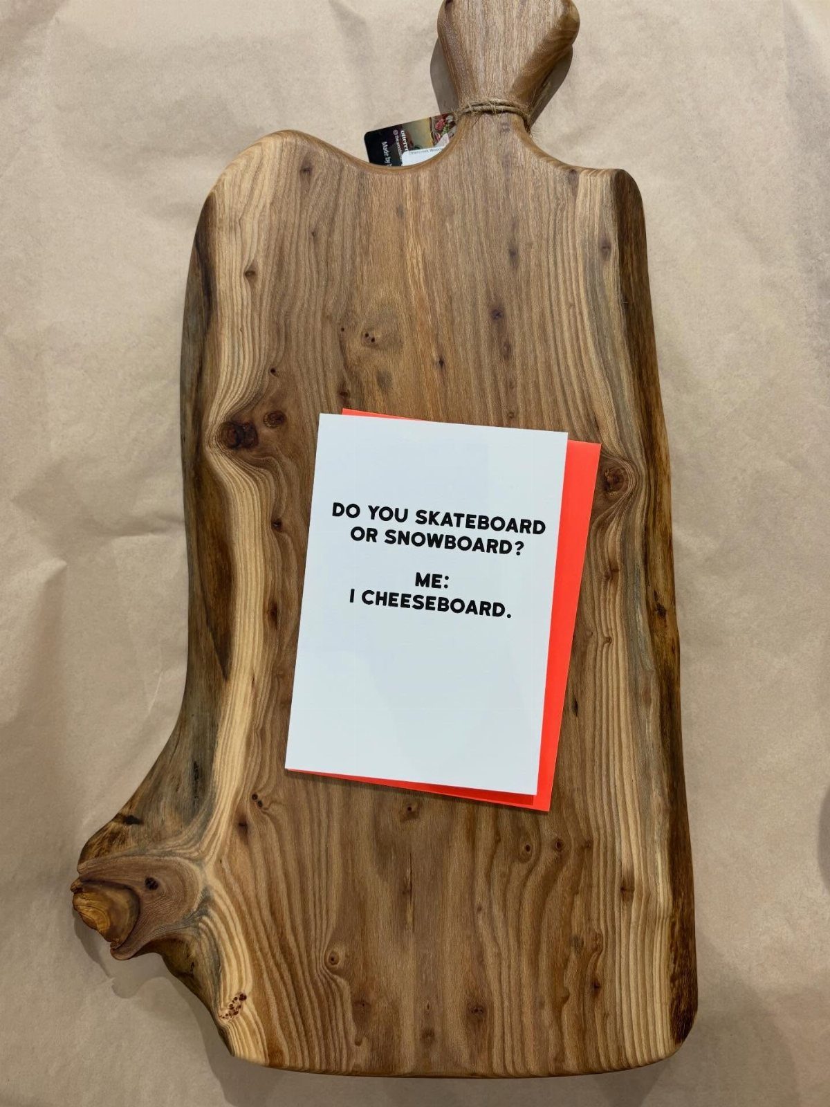 Wooden charcuterie board with a funny pun card about cheese boards on it.