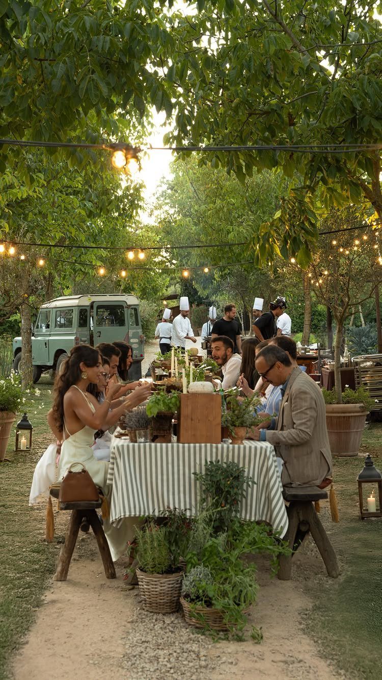 Outdoor dining table with striped cloth and natural decor under garden string lights