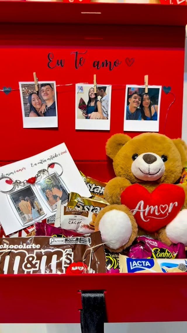 Red gift box with teddy bear, chocolates, and polaroid photos of a couple.