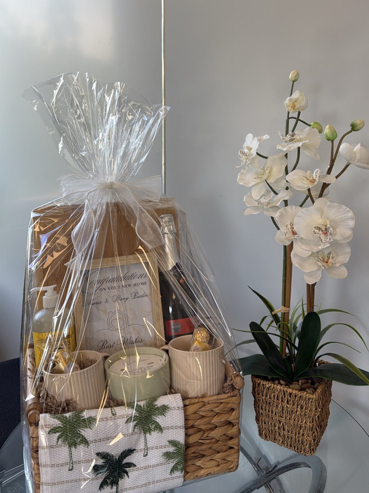 Wicker gift basket with wine, candle, and mugs wrapped in clear cellophane.