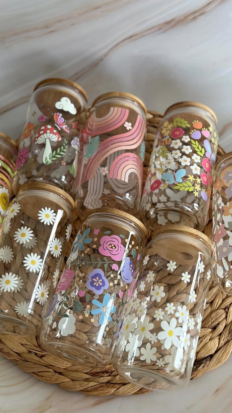 Decorated glass jars with wooden lids in a woven tray on marble surface