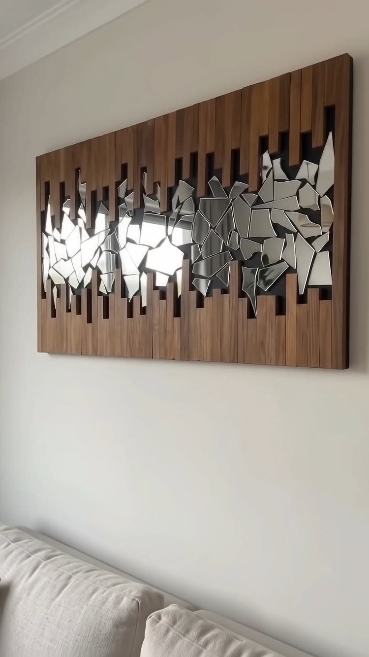 Wooden wall art with a mirrored mosaic inlay hanging on a white wall.
