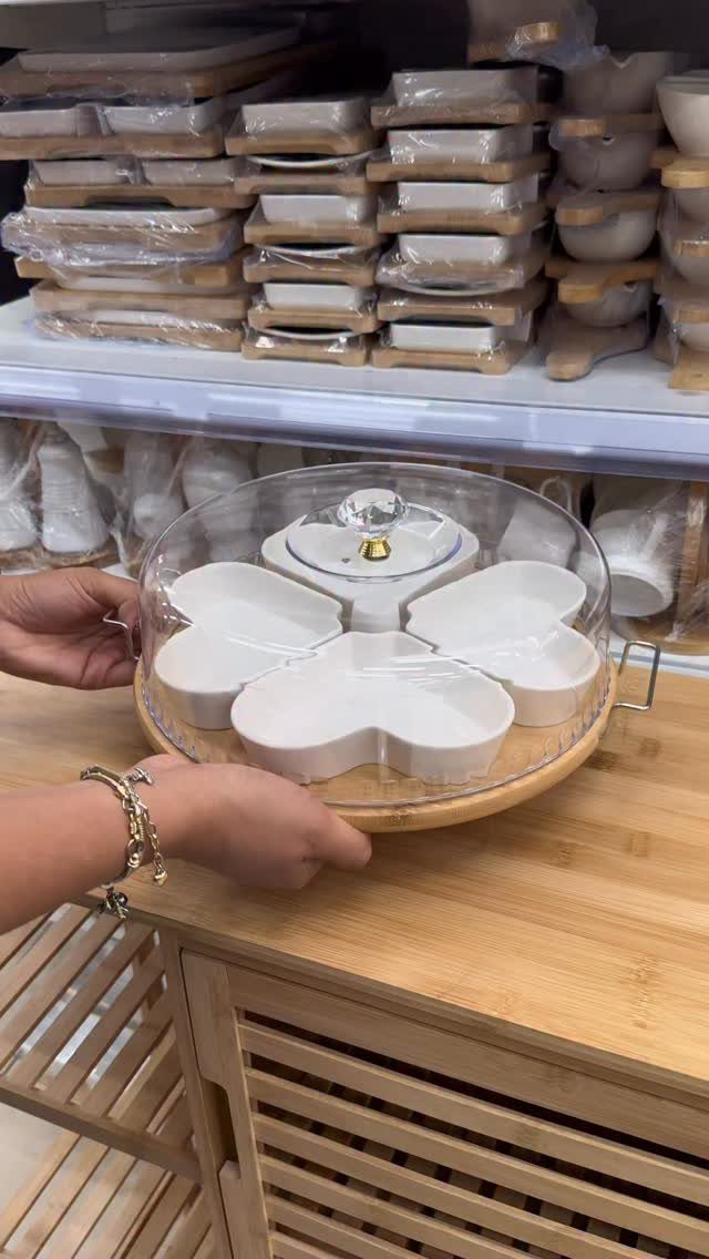 White ceramic divided serving tray with glass dome lid held by two hands.
