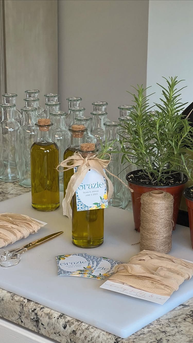Small glass bottles of olive oil with burlap bows and a rosemary plant.