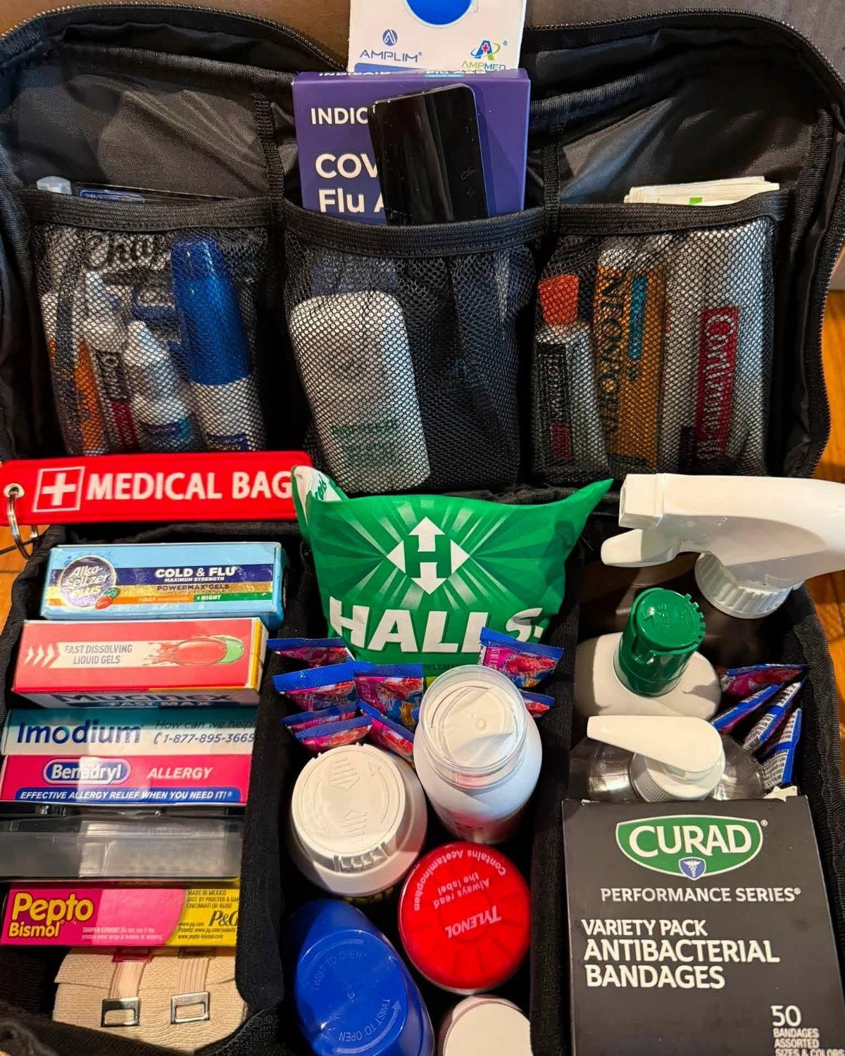 Open black medical bag containing antibacterial bandages, various medications, and first aid supplies.