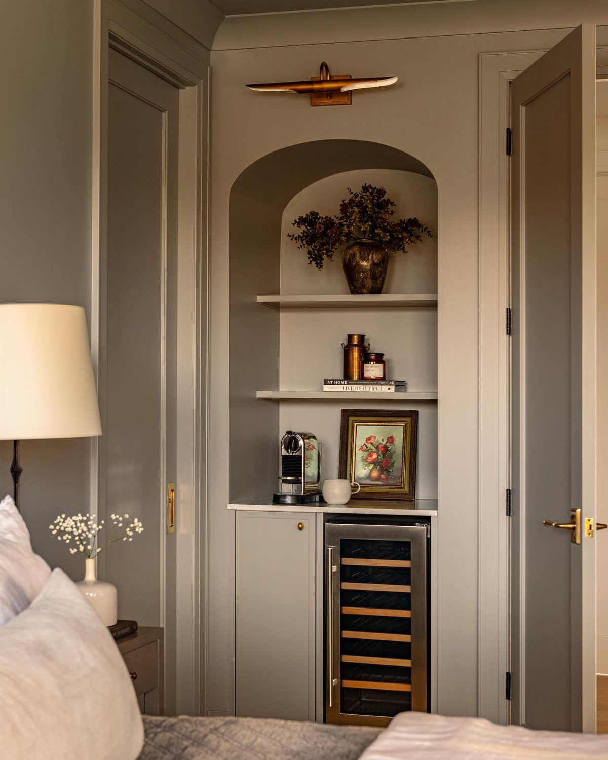 Small black coffee maker and white mug in a grey built-in bedroom nook.