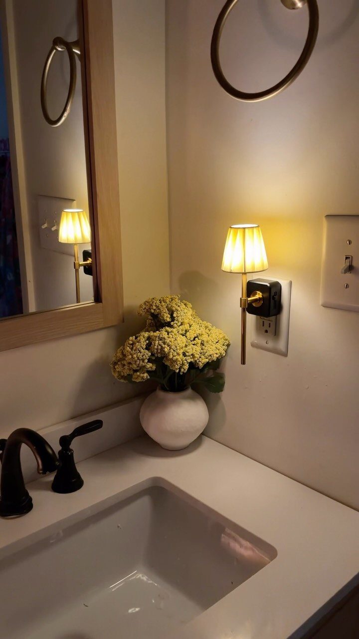Small lamp-style nightlight plugged into a bathroom wall next to yellow flowers.