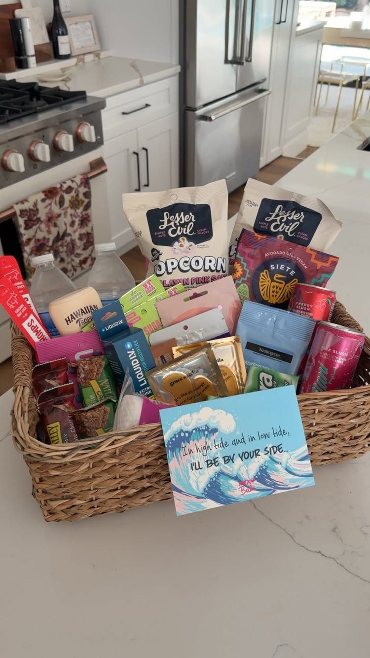 Wicker basket filled with assorted packaged snacks and water on a white counter.