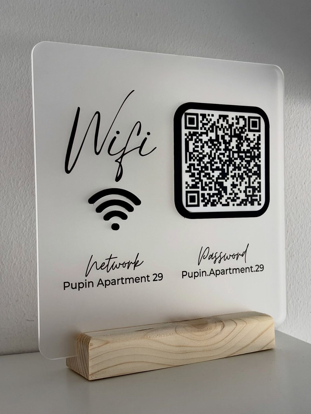Wifi password sign with QR code in a wooden base on white surface