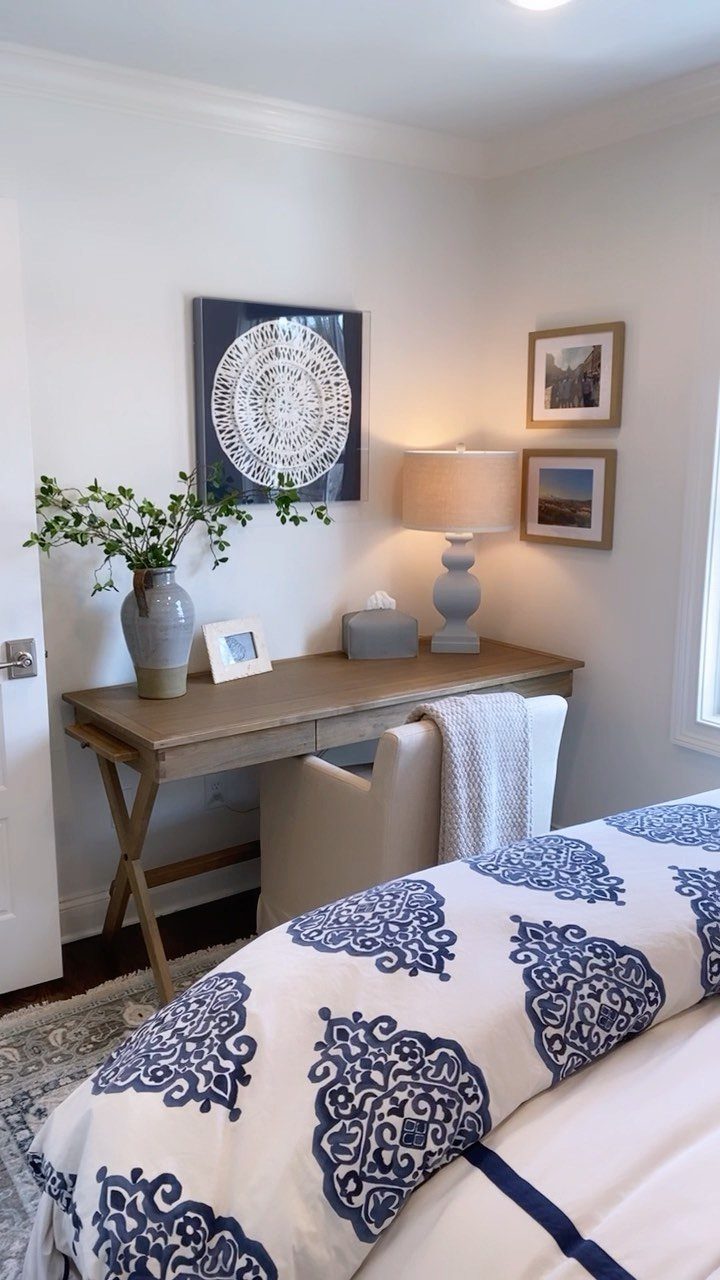 Wooden desk and chair set up next to a bed with blue patterns.