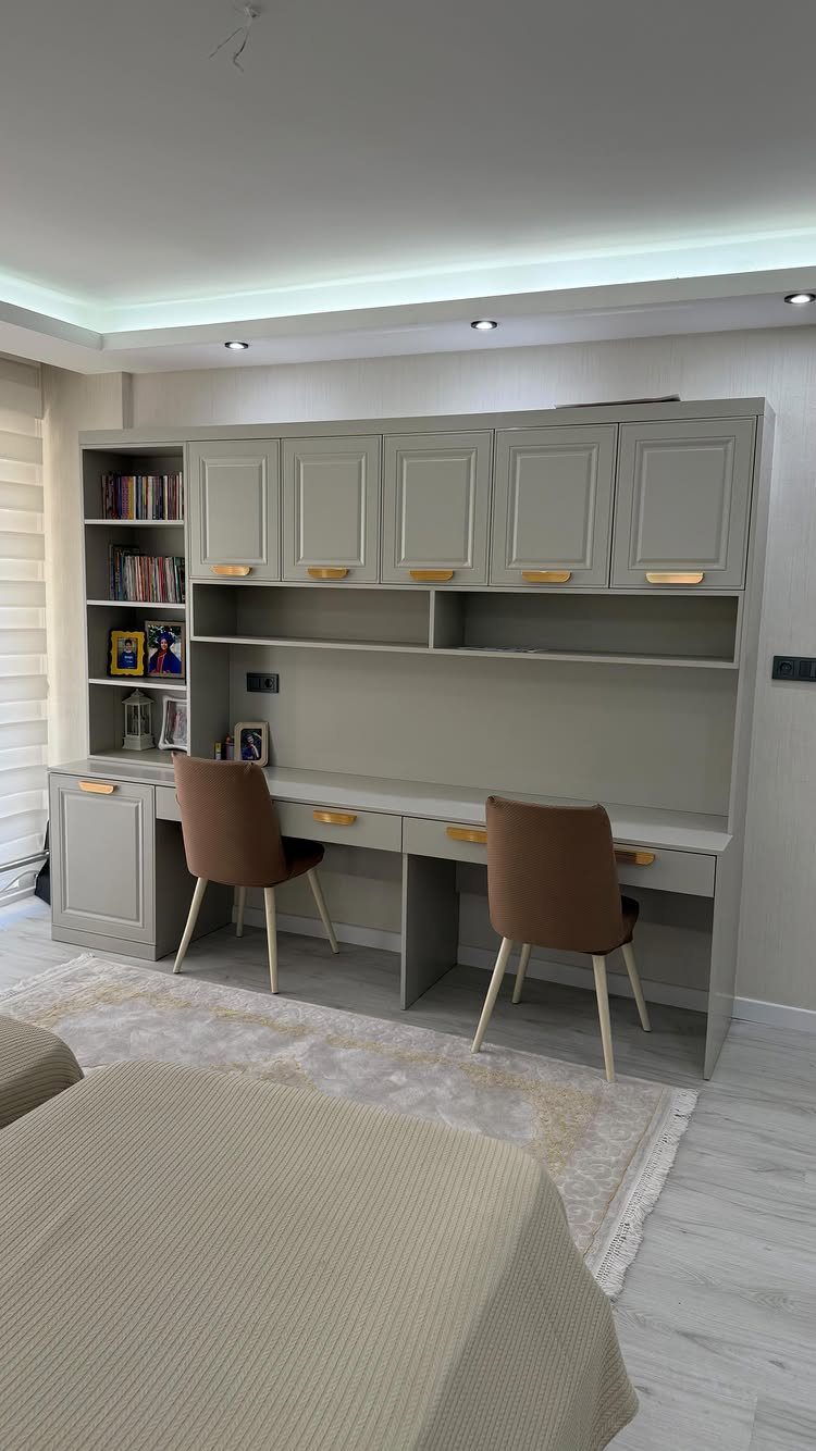 Built-in grey desk and shelving unit in a room with a bed.
