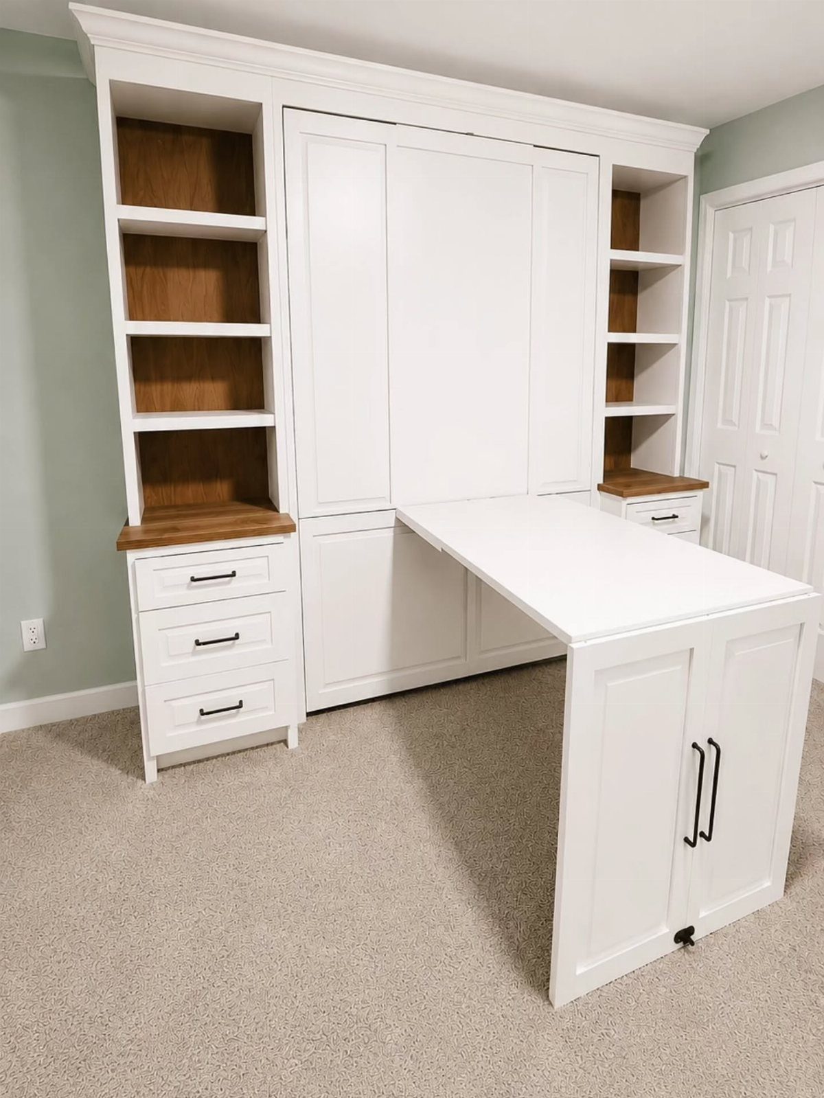 White built-in wall unit with a fold-out desk and integrated shelving.