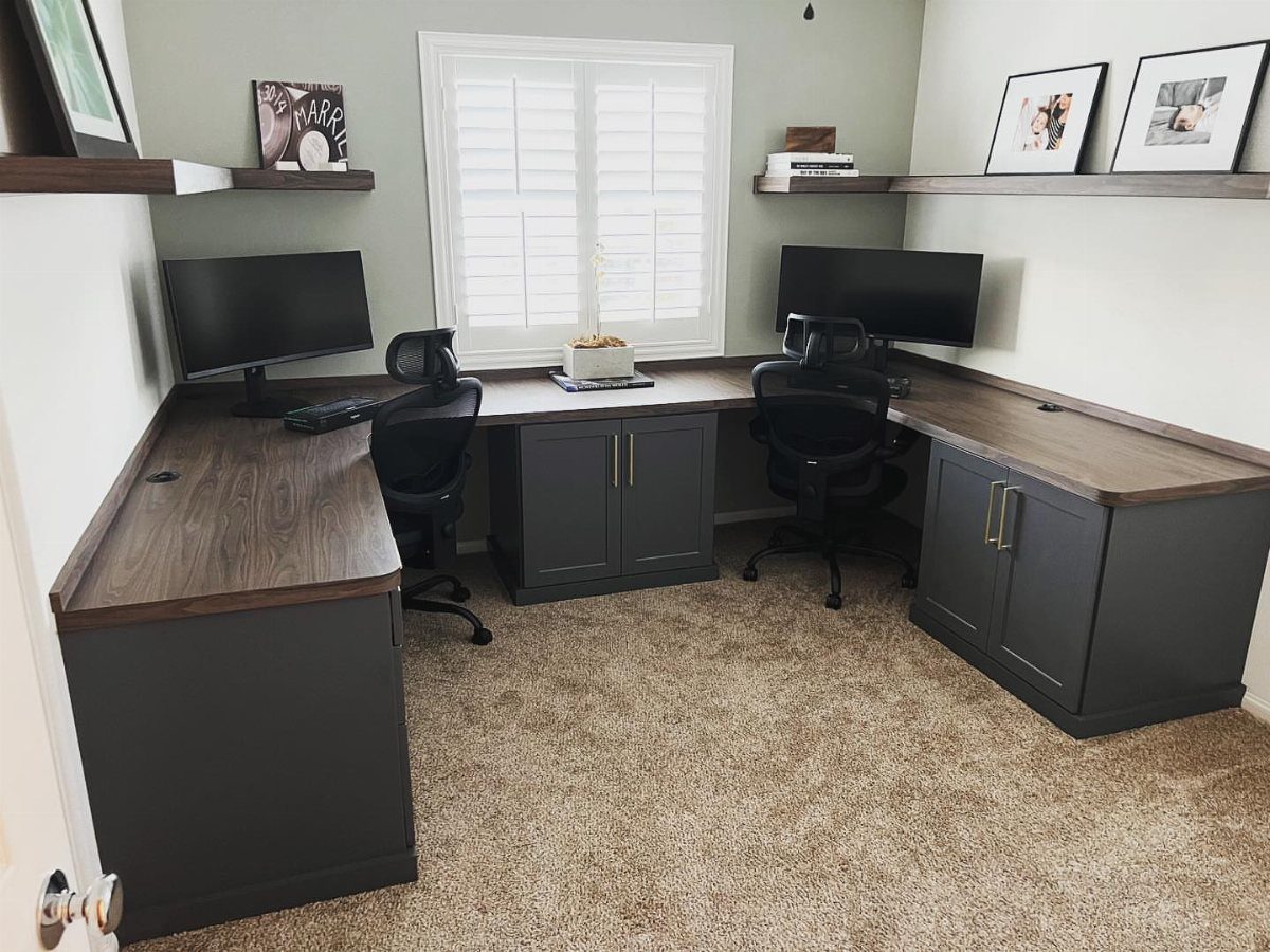 L-shaped wrap-around desk with two monitors and black office chairs in a home office.