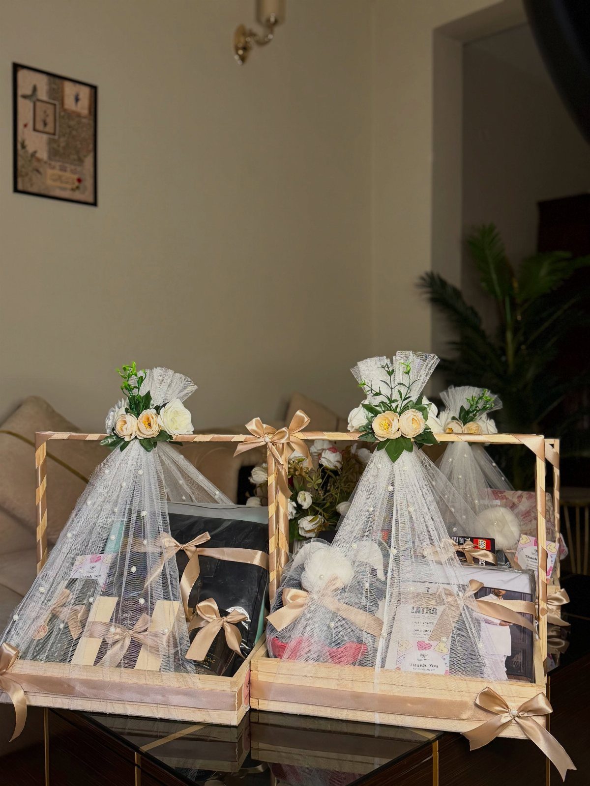 Gold-framed gift baskets wrapped in white tulle with floral decorations and gold ribbons.