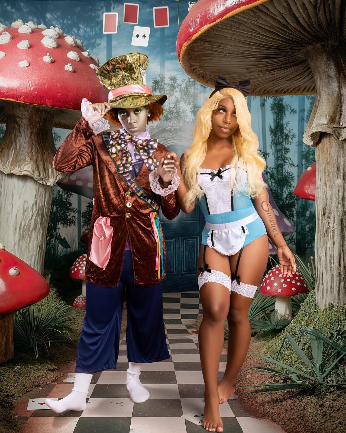 Couple dressed as the Mad Hatter and Alice in a whimsical mushroom forest.