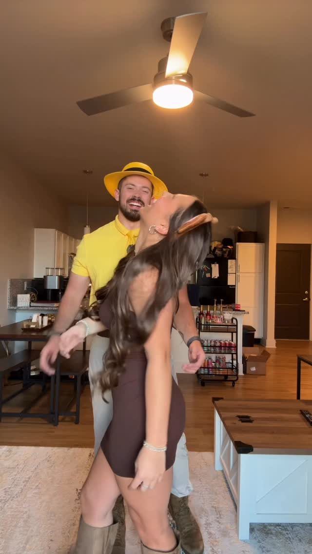 Man in yellow hat and shirt with woman in brown dress posing together.