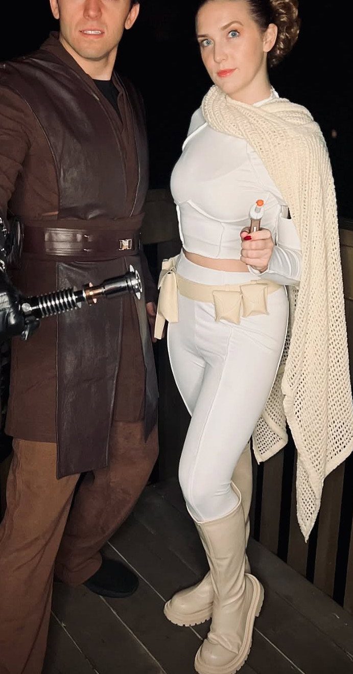 Man and woman dressed as Han Solo and Princess Leia posing outdoors at night.