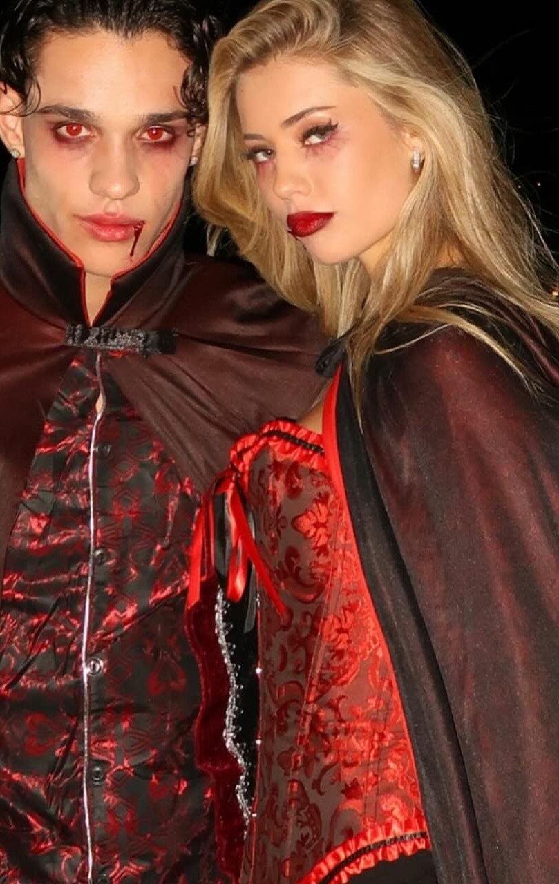 Couple dressed as vampires wearing red and black gothic attire with fake blood.