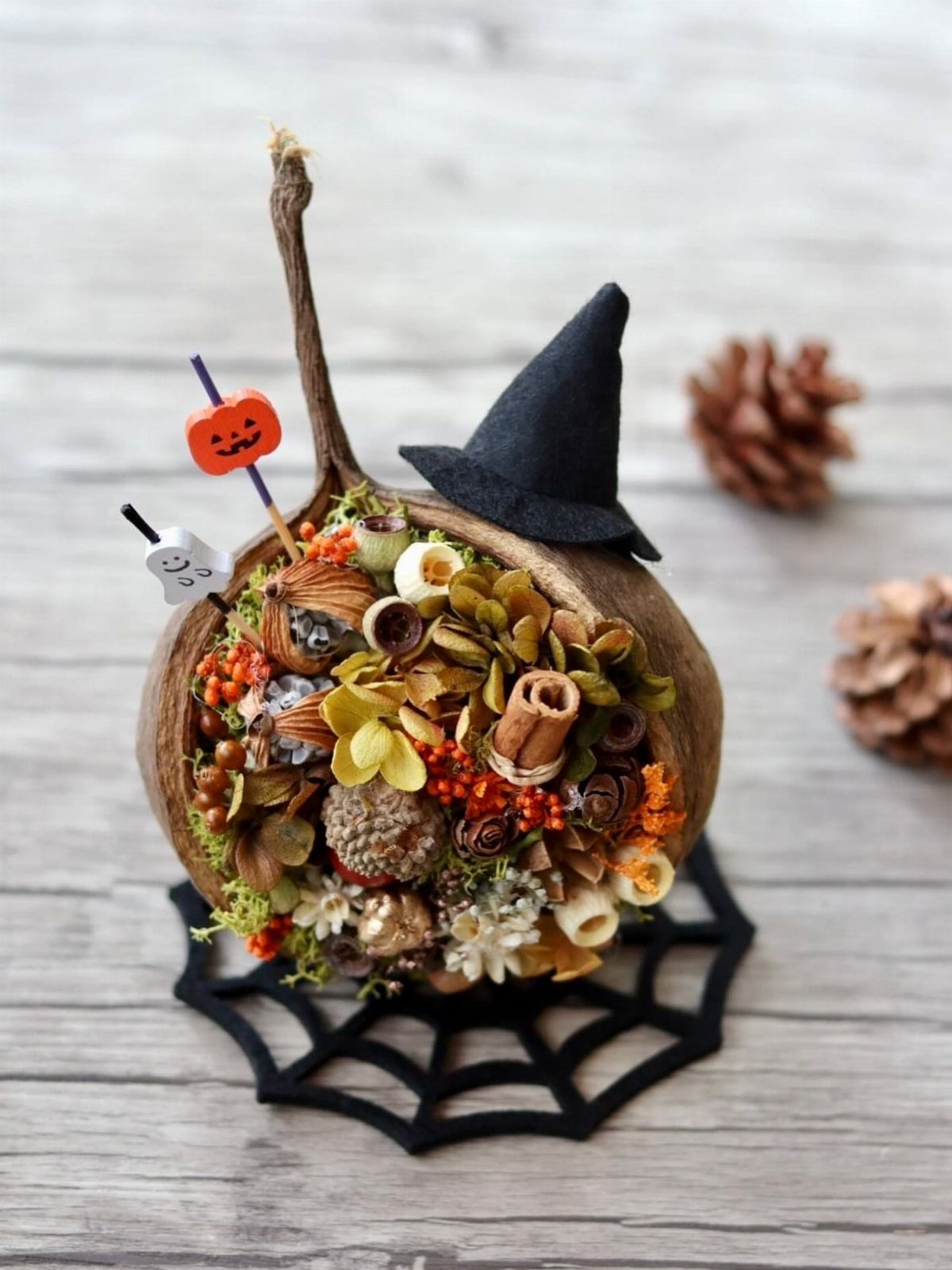 Hollowed pumpkin filled with dried flowers, cinnamon sticks, and a tiny witch hat.