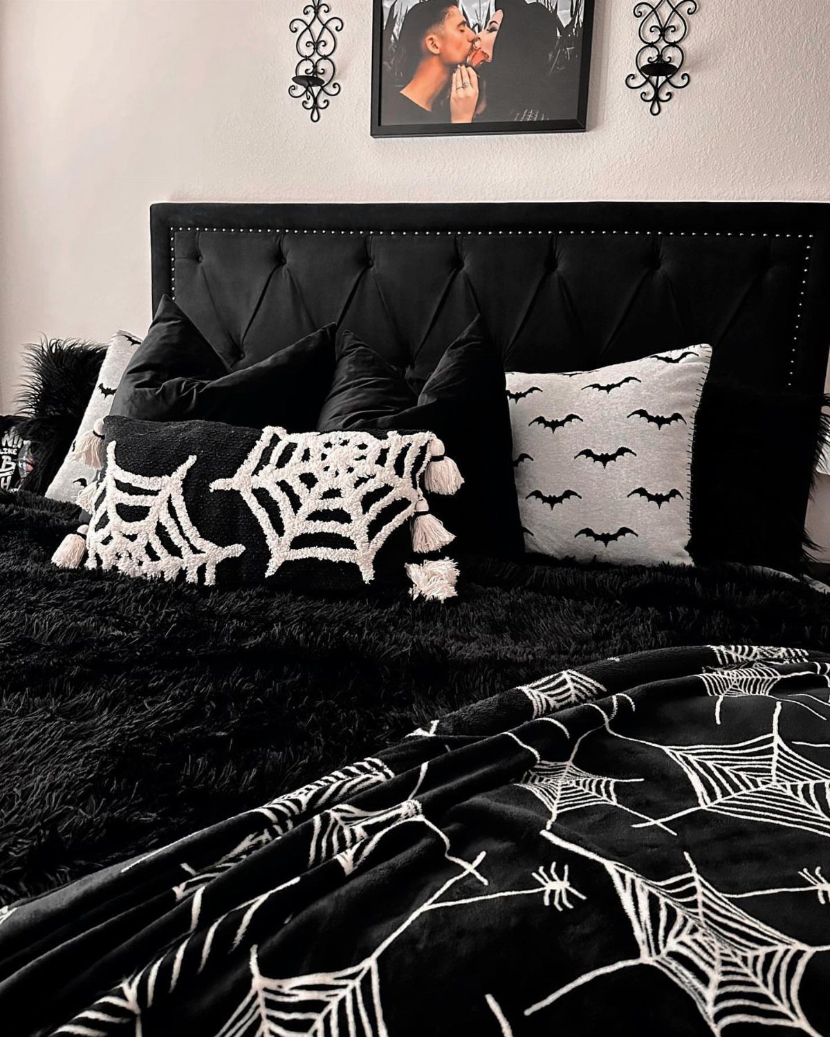 Bed with black and white spiderweb and bat themed Halloween bedding and pillows.
