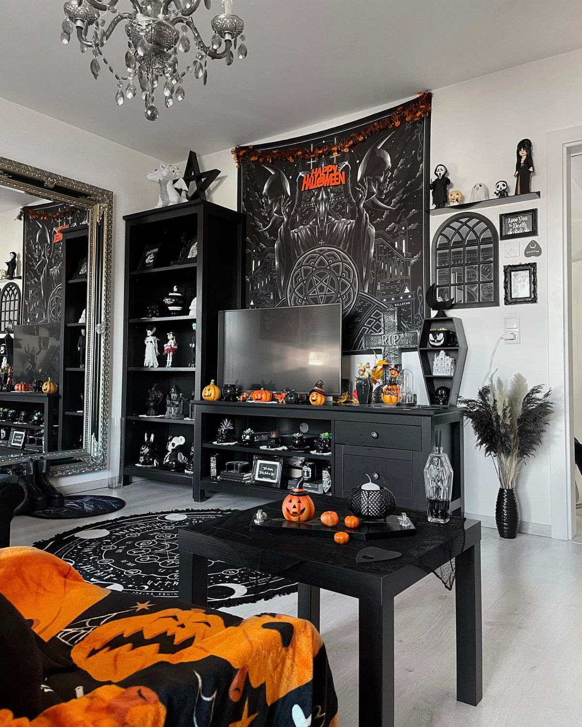 Halloween decorated living room with black furniture, pumpkins, and a large ornate mirror.
