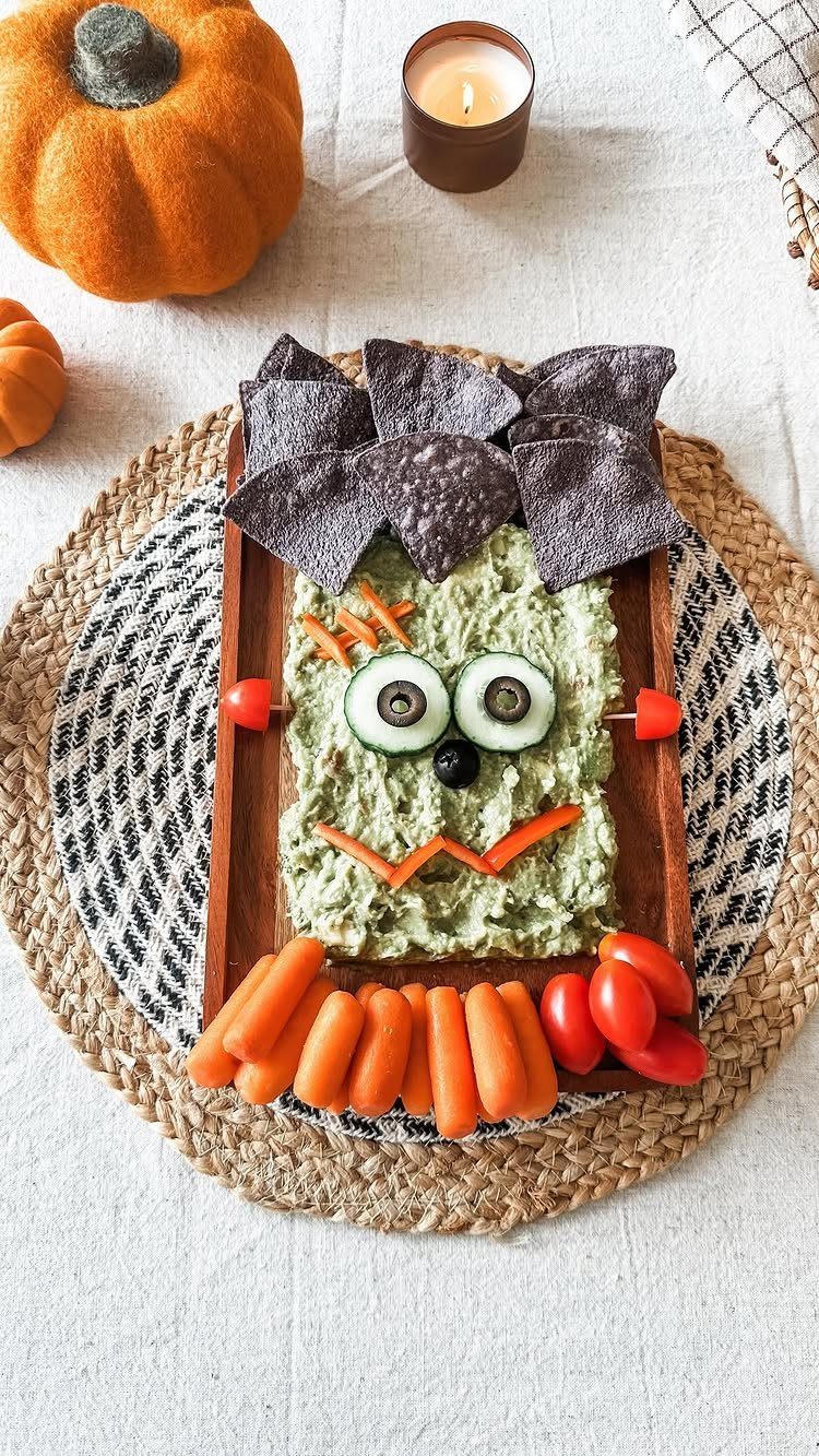 Guacamole styled as Frankenstein's face with vegetable accents and blue tortilla chips.