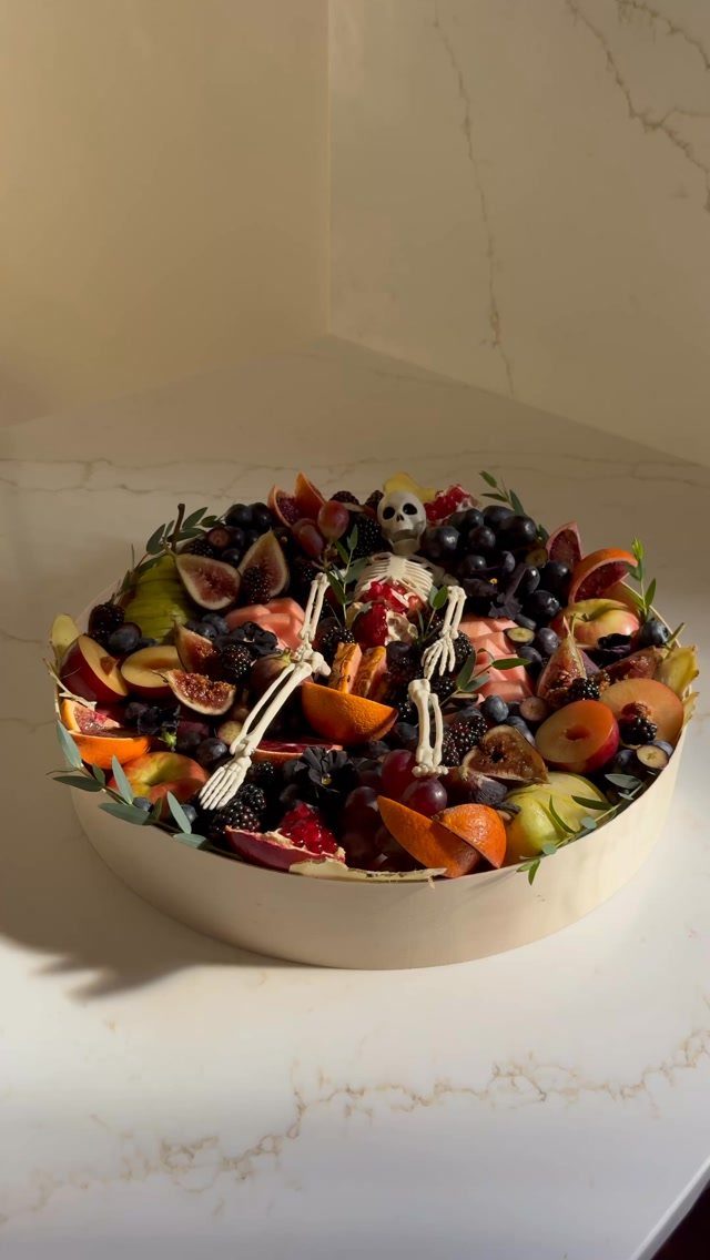 Fruit platter with a small skeleton figure resting on top of mixed berries.