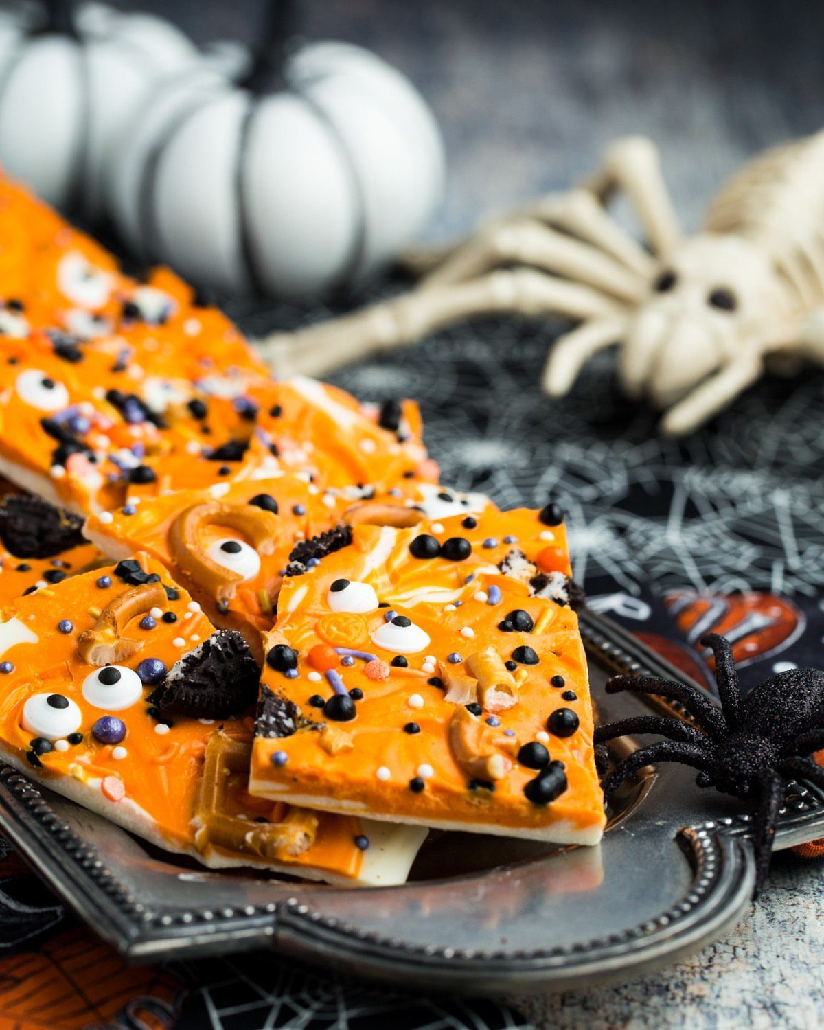 Orange and white chocolate Halloween bark with candy eyes and pretzels on silver platter