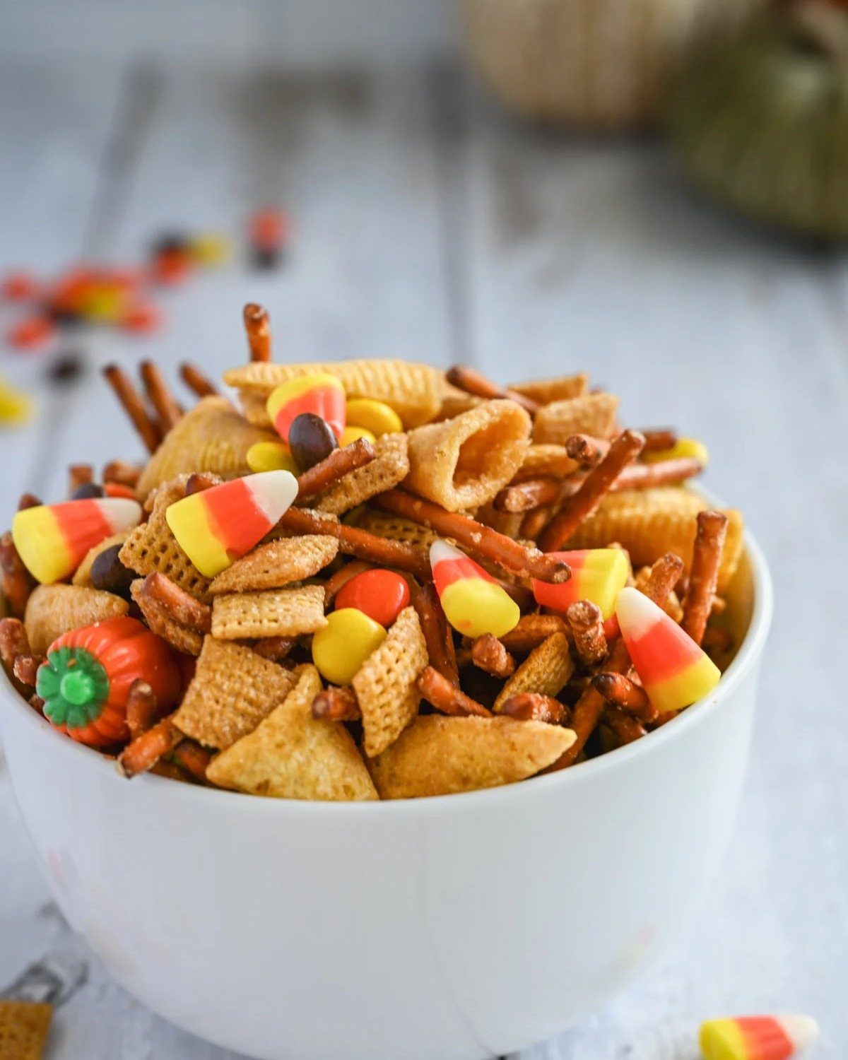Halloween snack mix with candy corn and pretzels in a white bowl.