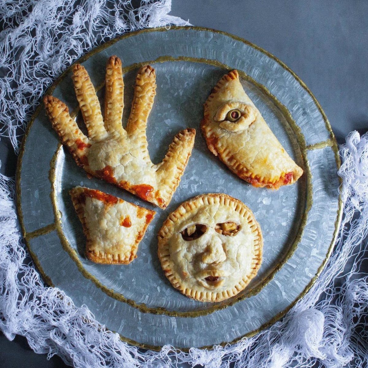 Savory hand pies shaped like a hand and face on a blue plate.