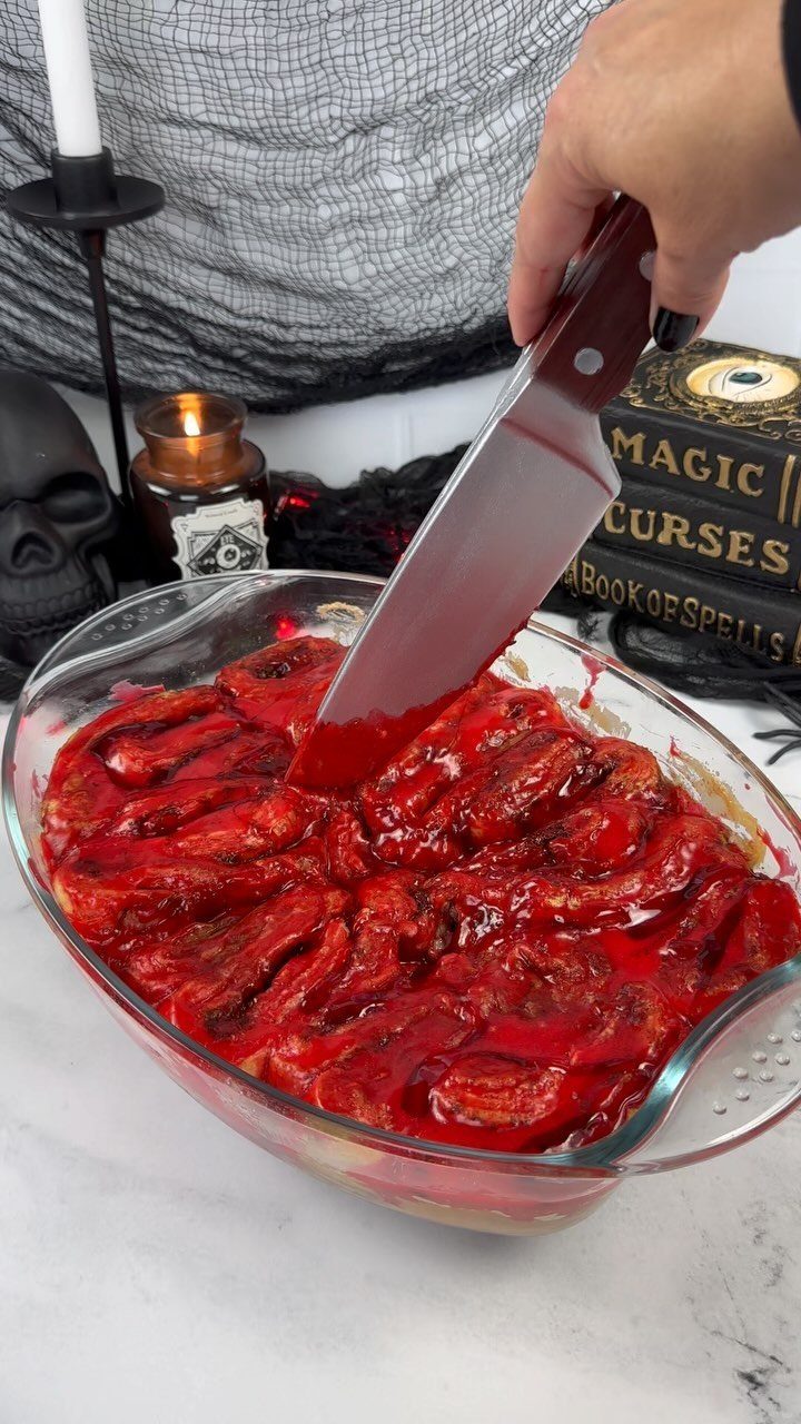Brain-shaped red dip in a glass dish being cut with a knife.