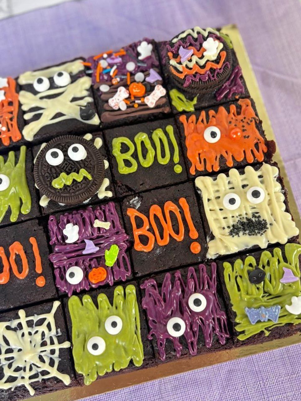 Halloween brownies decorated with colorful frosting, candy eyes, and spooky themed designs.
