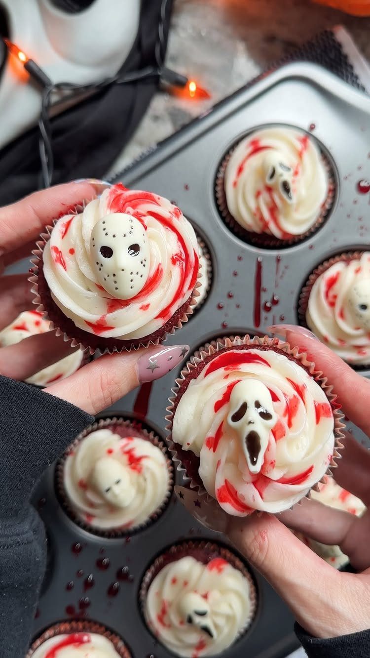 Halloween cupcakes with white frosting, red syrup, and horror movie character masks.