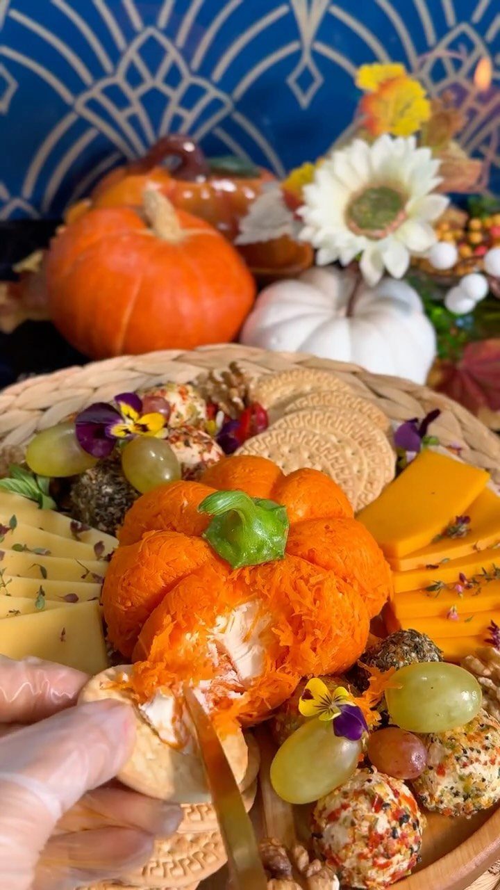 Pumpkin shaped cheese ball on a party platter with crackers and grapes